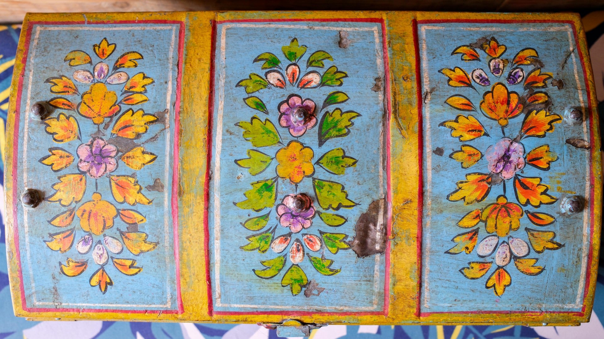 Decorative metal dome trunk with floral patterns on a blue background