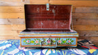 Decorative metal trunk with floral patterns on a colorful fabric background