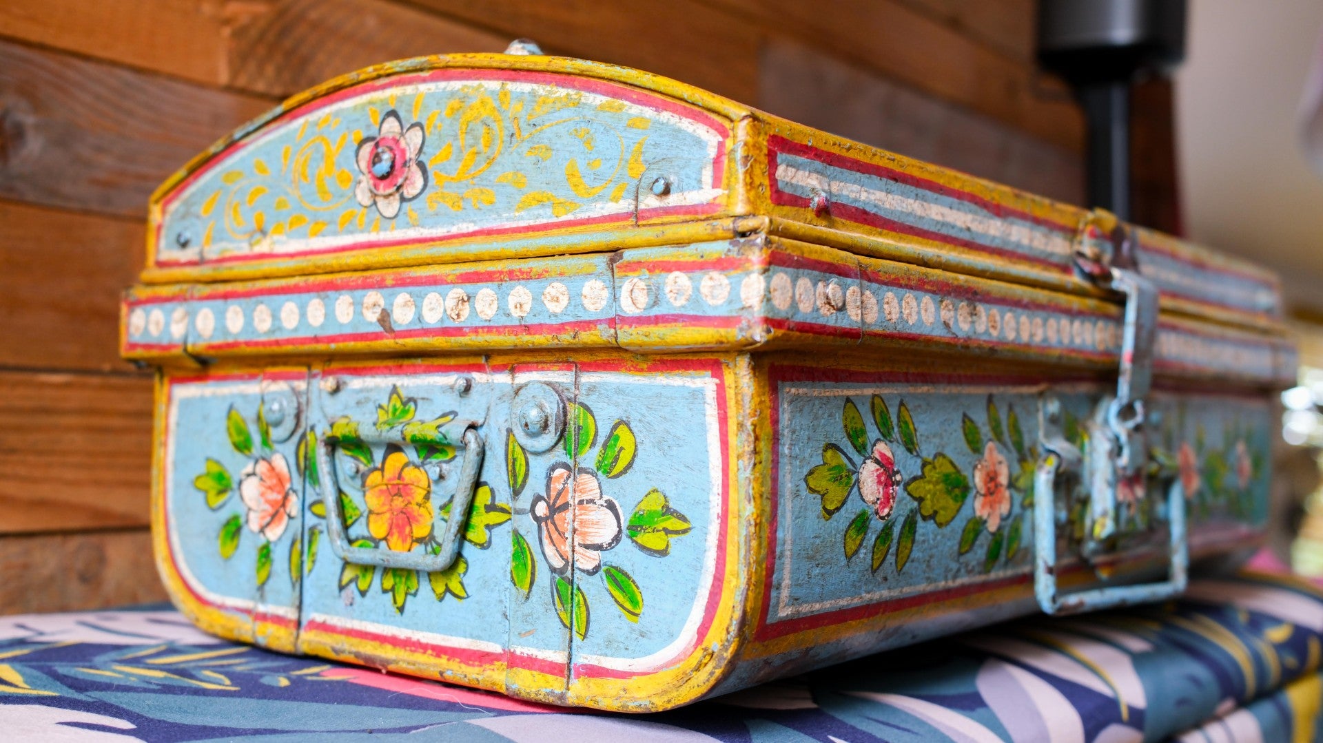 Decorative metal box with floral patterns on a patterned surface