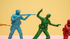 Toy soldiers in blue, green, and red on a yellow and pink background