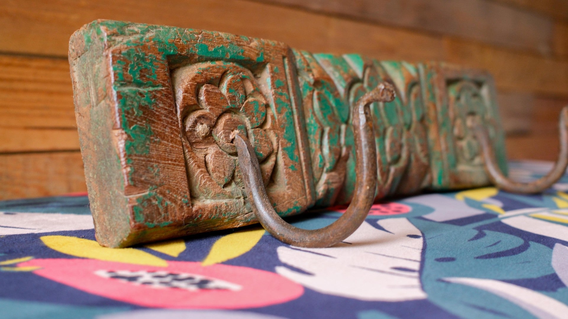 Decorative metal hook with intricate design on a colorful fabric background