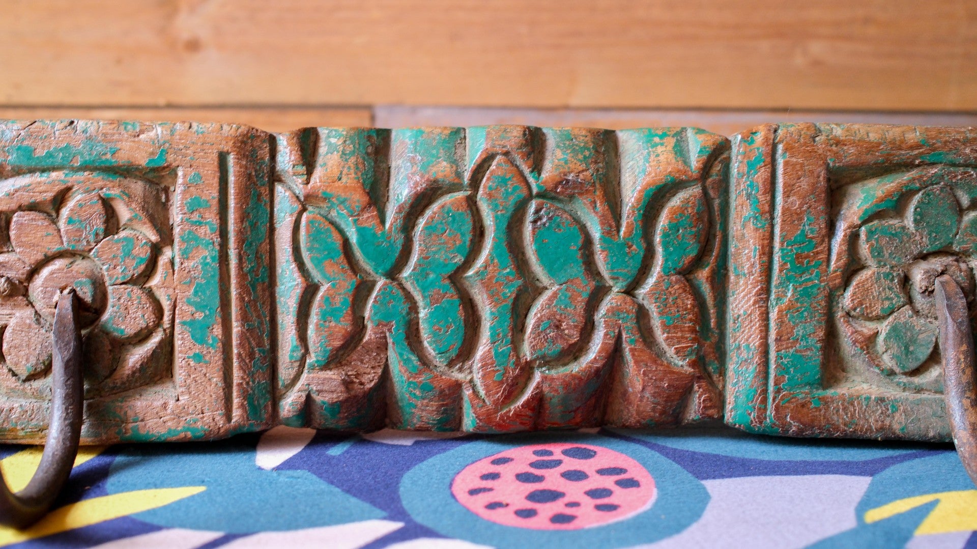 Decorative metal wall art with intricate patterns on a colorful fabric background