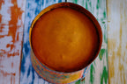 Colorful floral hand painted bucket on a table with a multicolored geometric patterned wall in the background
