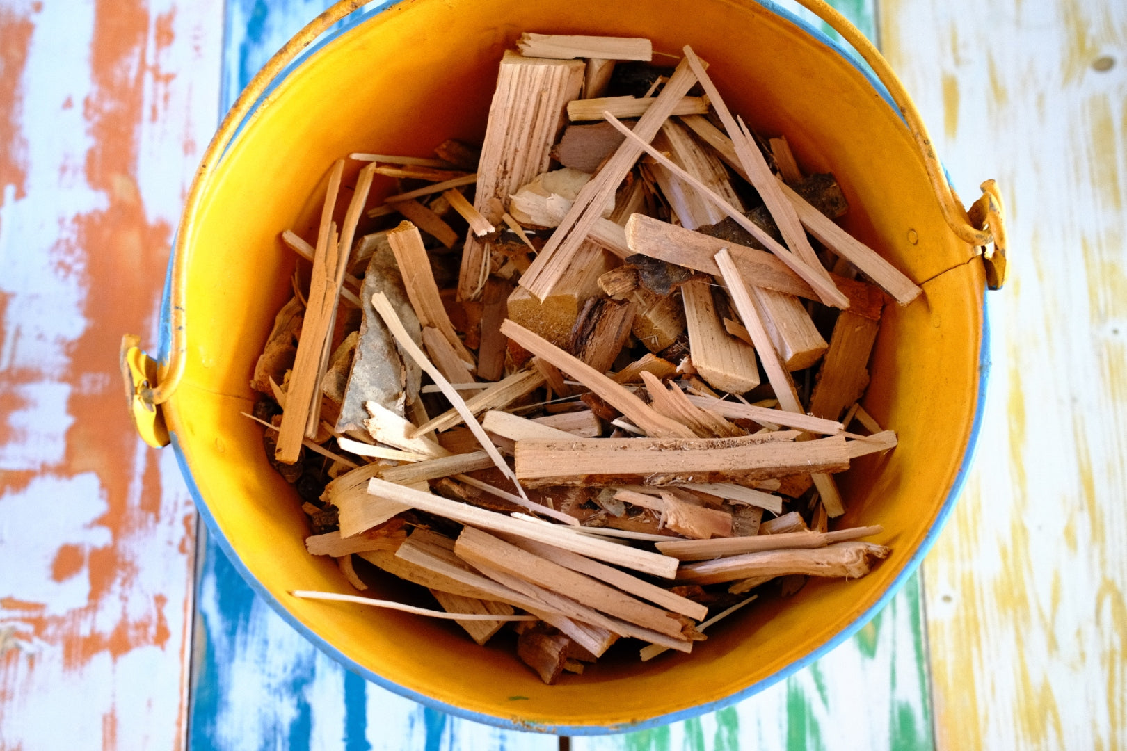 Yellow bucket filled with kindling on a colorful background