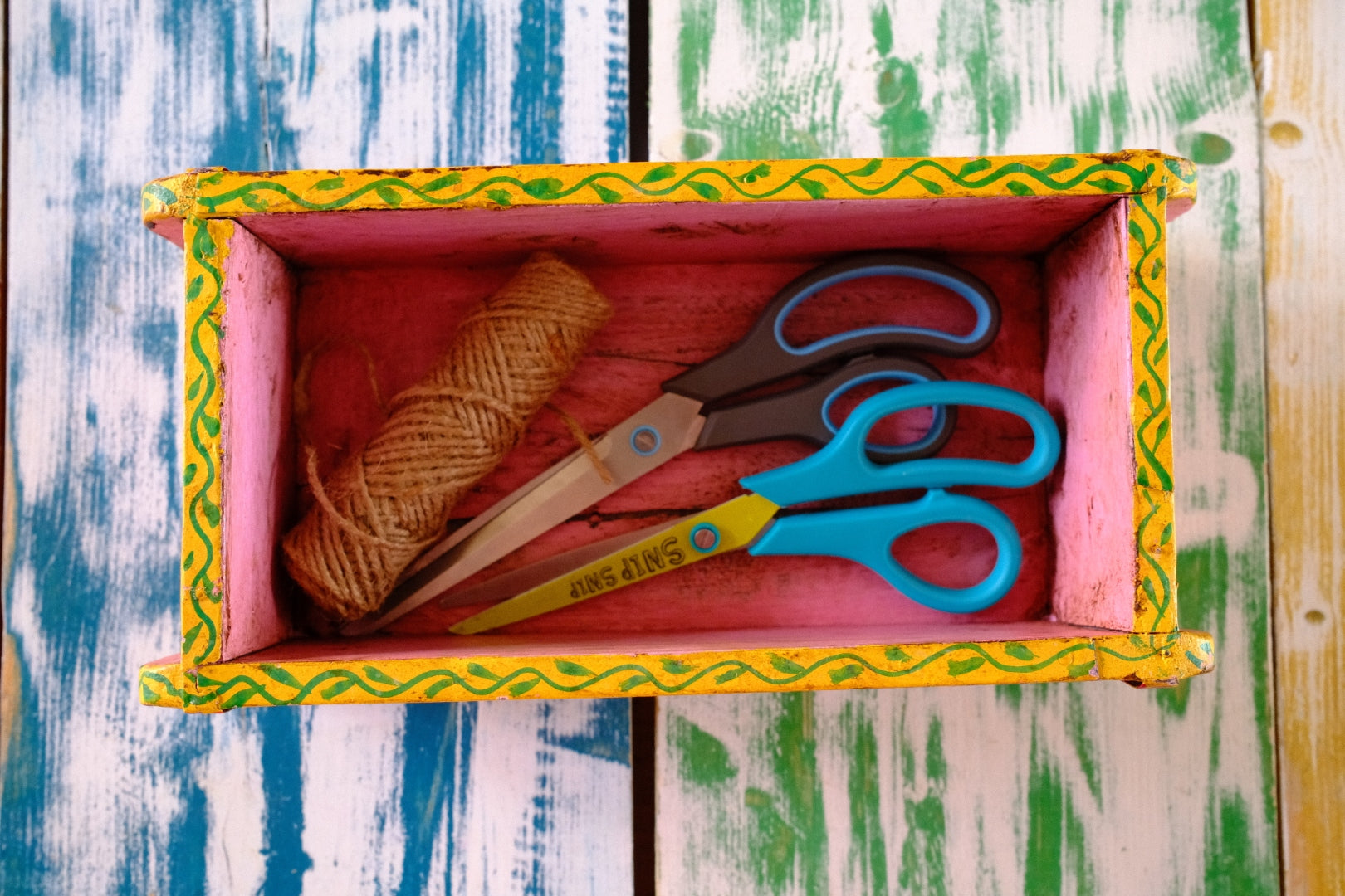 Colorful box with yarn and scissors on a wooden surface