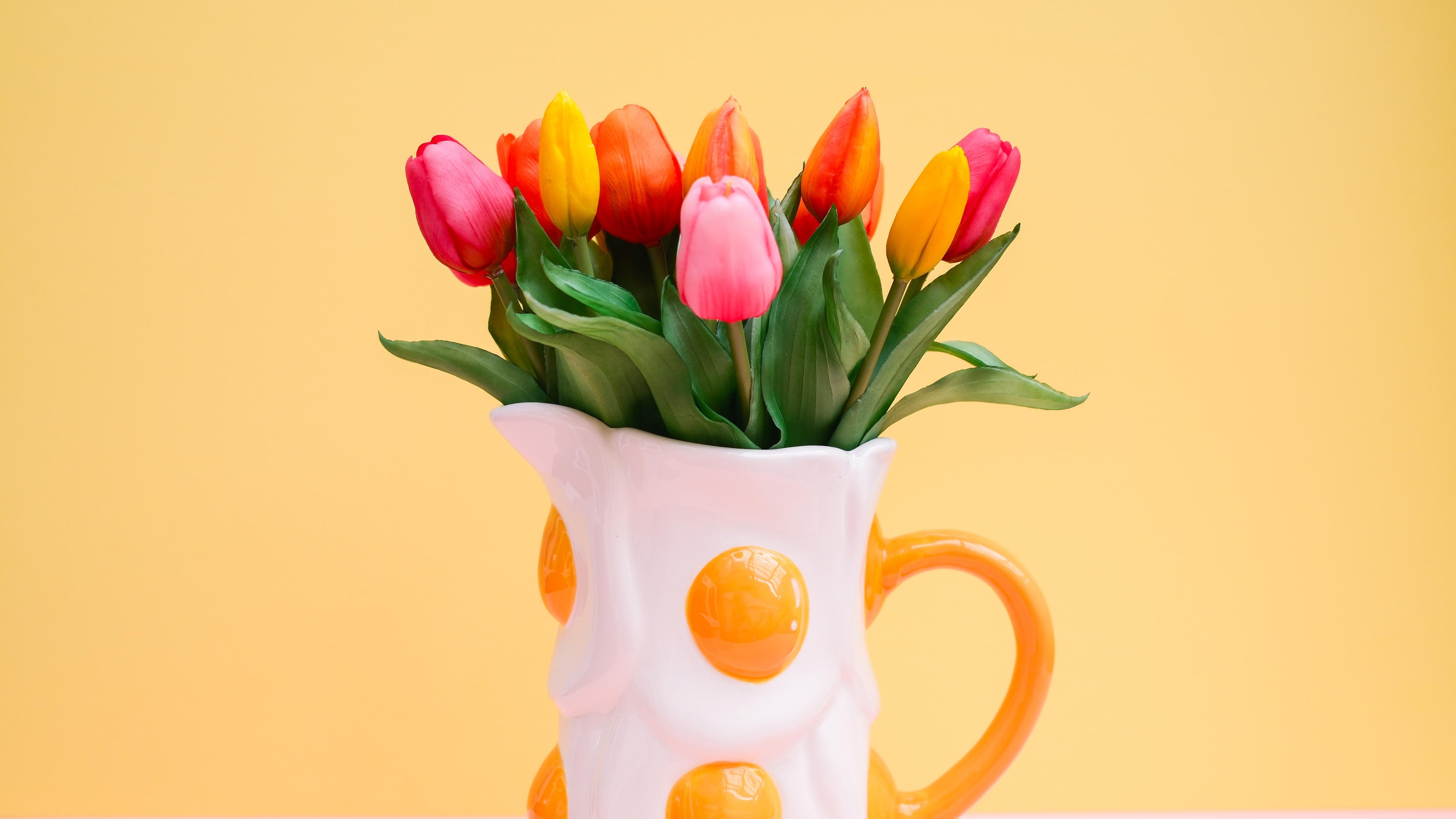 Egg jug with colorful tulips on a yellow background