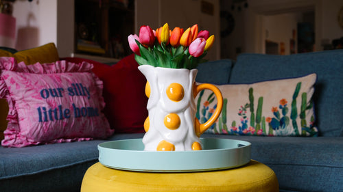 Colorful jug mug with flowers on a tray in a living room setting