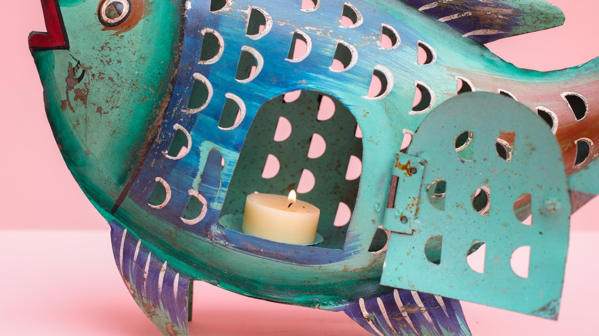 Decorative fish-shaped lantern with a candle inside on a pink background