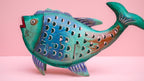 Decorative fish sculpture with a rustic finish on a pink background