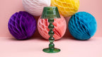 Green glass tealight lamp with colorful honeycomb balls on a pink background