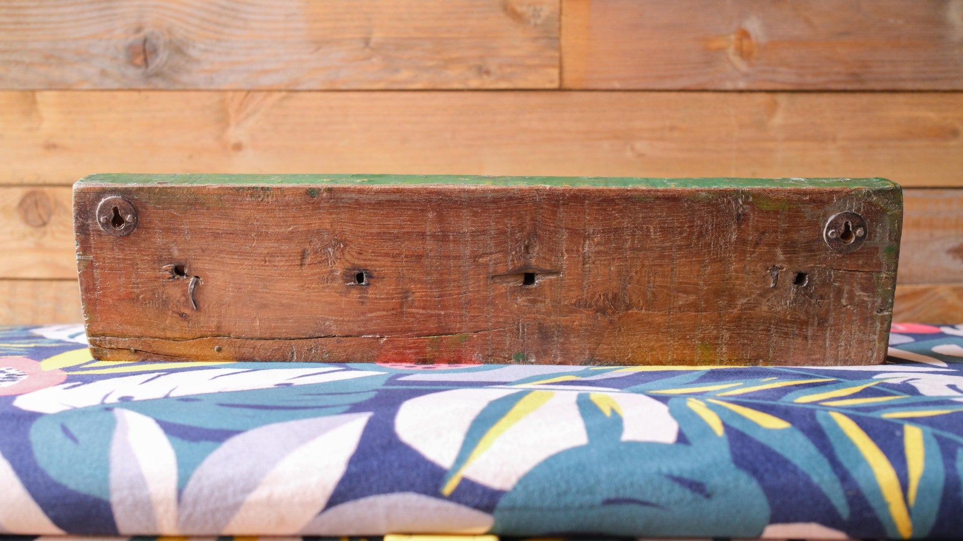 Wooden bench with floral cushion on a wooden floor