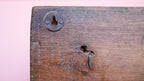 Close-up of an old wooden door with a lock and keyhole on a pink background