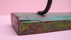Vintage-style metal block with a handle on a pink background