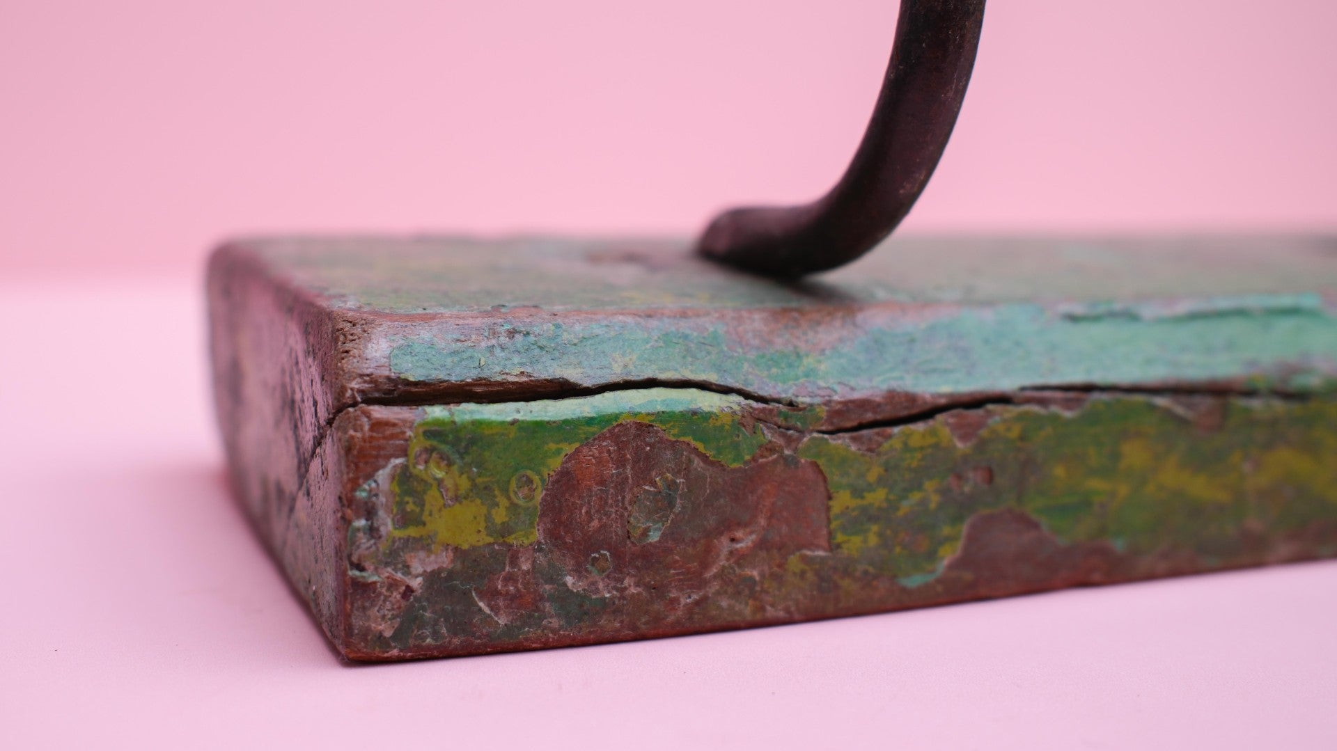 Vintage-style metal block with a handle on a pink background
