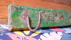 Vintage green suitcase with a rusty handle on a colorful fabric background