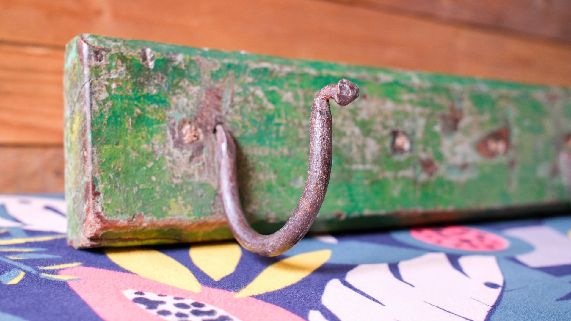 Vintage green suitcase with a rusty handle on a colorful fabric background