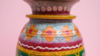 Decorative wooden pot with colorful patterns on a pink background