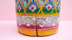 Decorative wooden pot with colorful patterns on a pink background