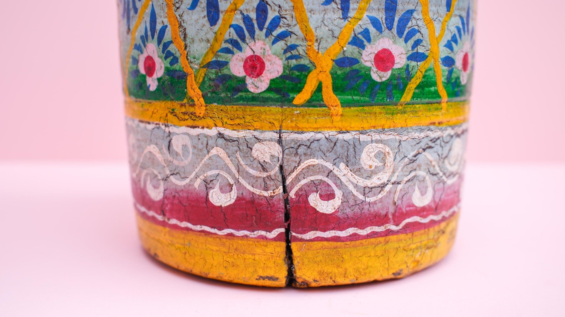 Decorative wooden pot with colorful patterns on a pink background
