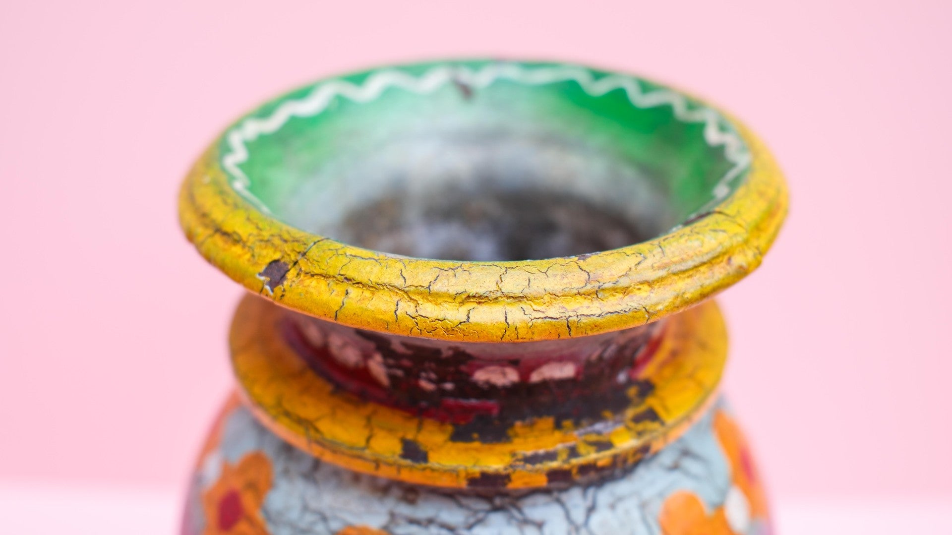 Decorative pot with cracked paint on a pink background