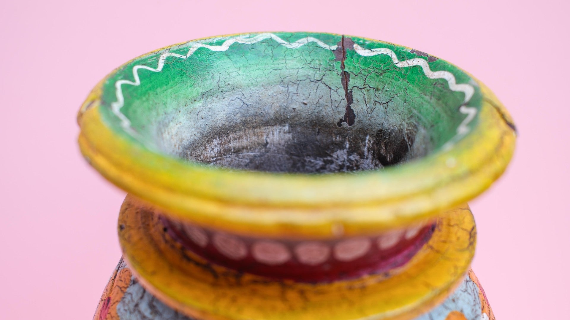 Decorative wooden pot with cracked glaze on a pink background