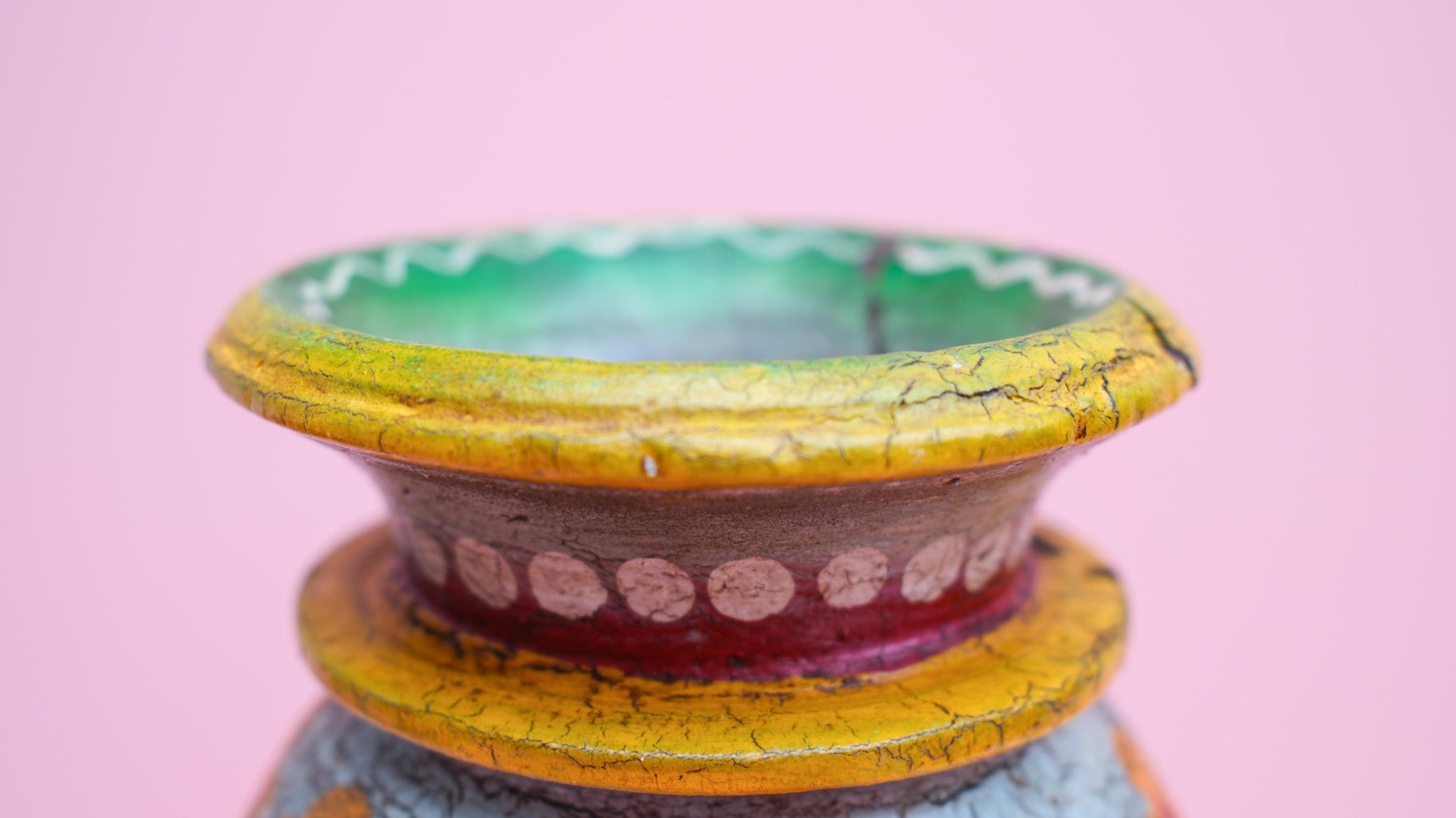 Decorative pot with a colorful design on a pink background
