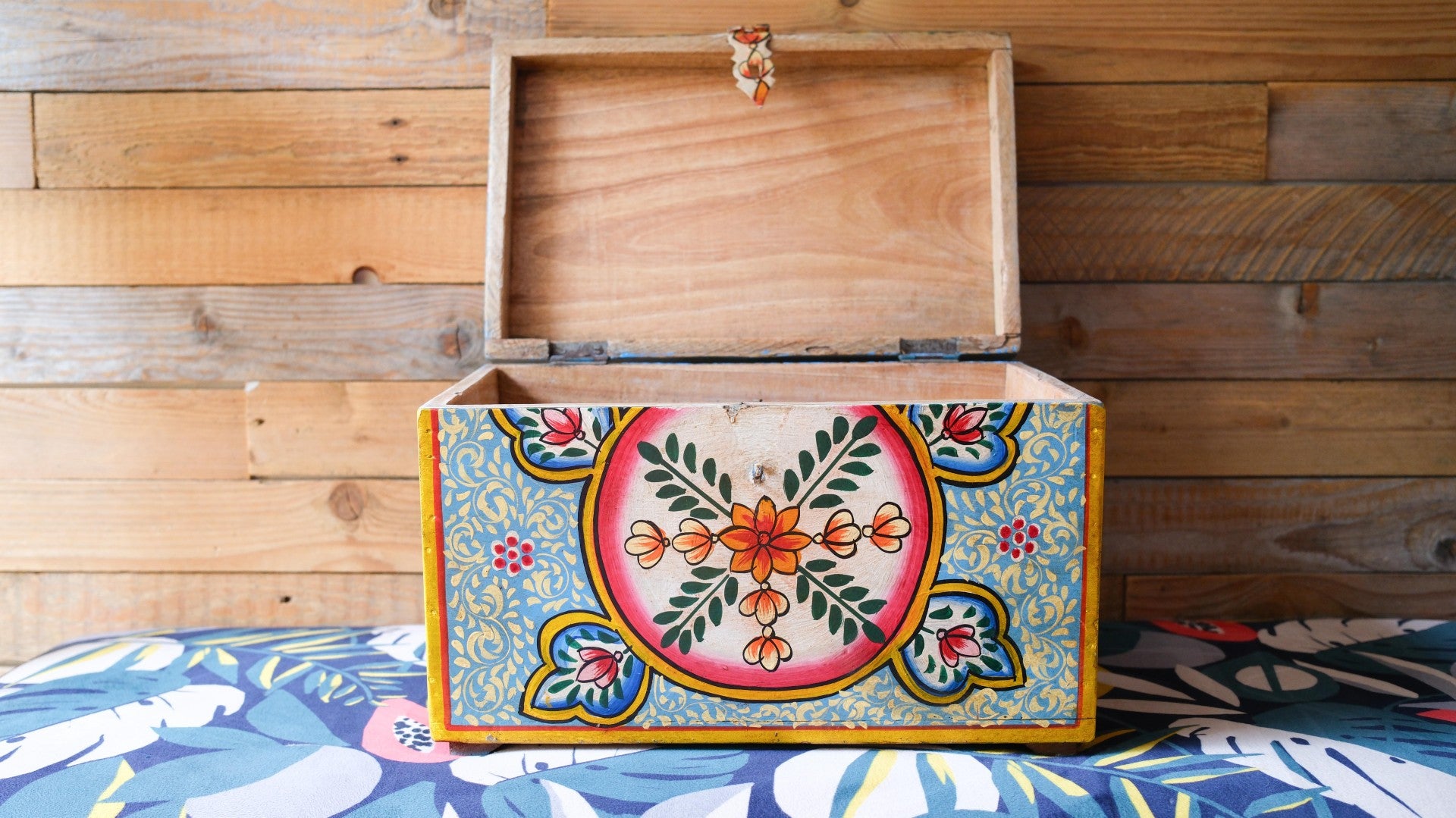 Wooden box with colorful floral design on a wooden background