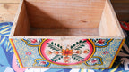 Wooden box with colorful floral design on a patterned surface