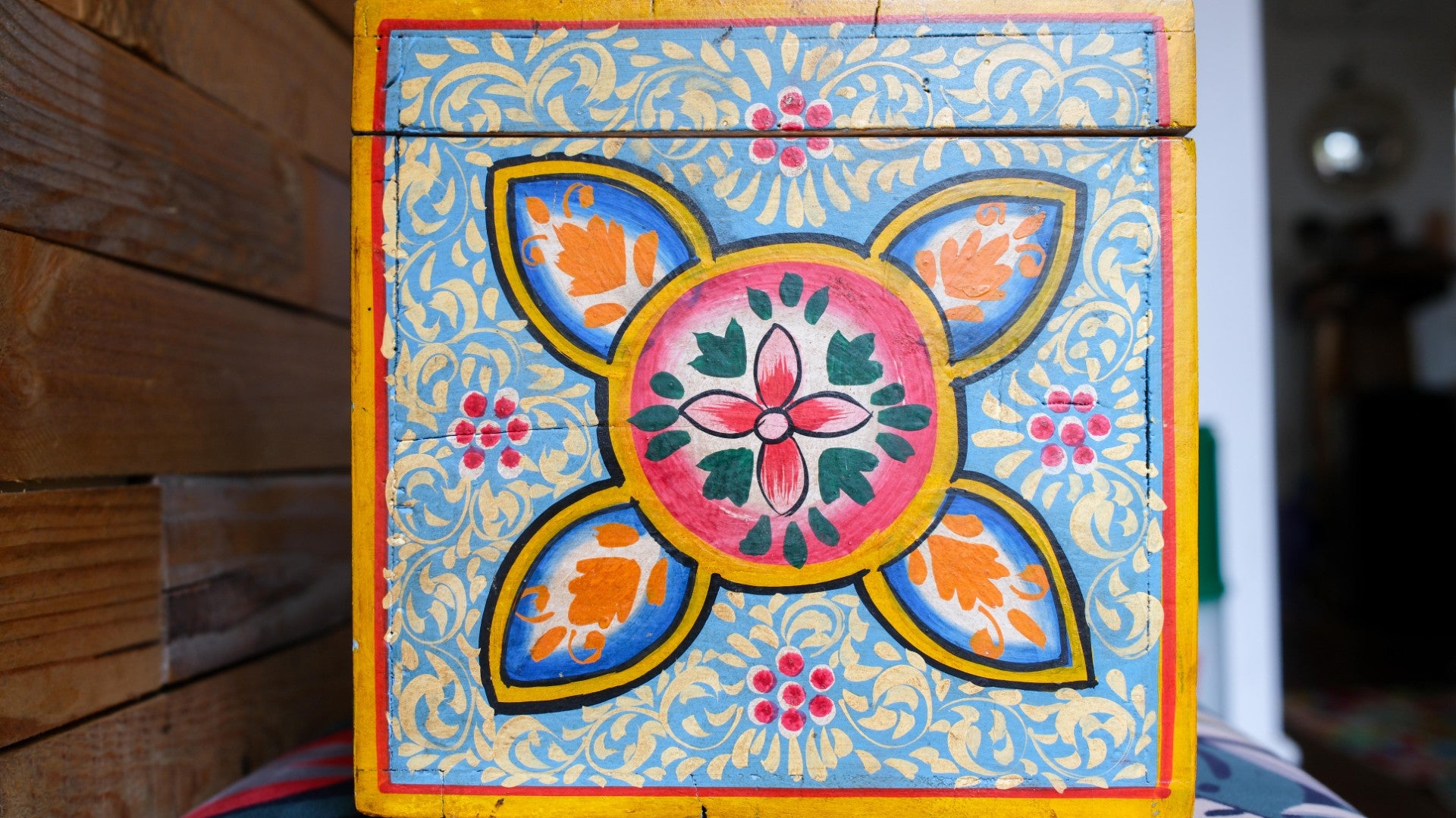 Decorative box with colorful floral design on a wooden surface