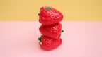 Stack of red strawberry-shaped objects on a pink and yellow gradient background