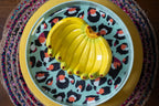 Decorative banana dish with a pattern of yellow bananas on a colorful woven surface