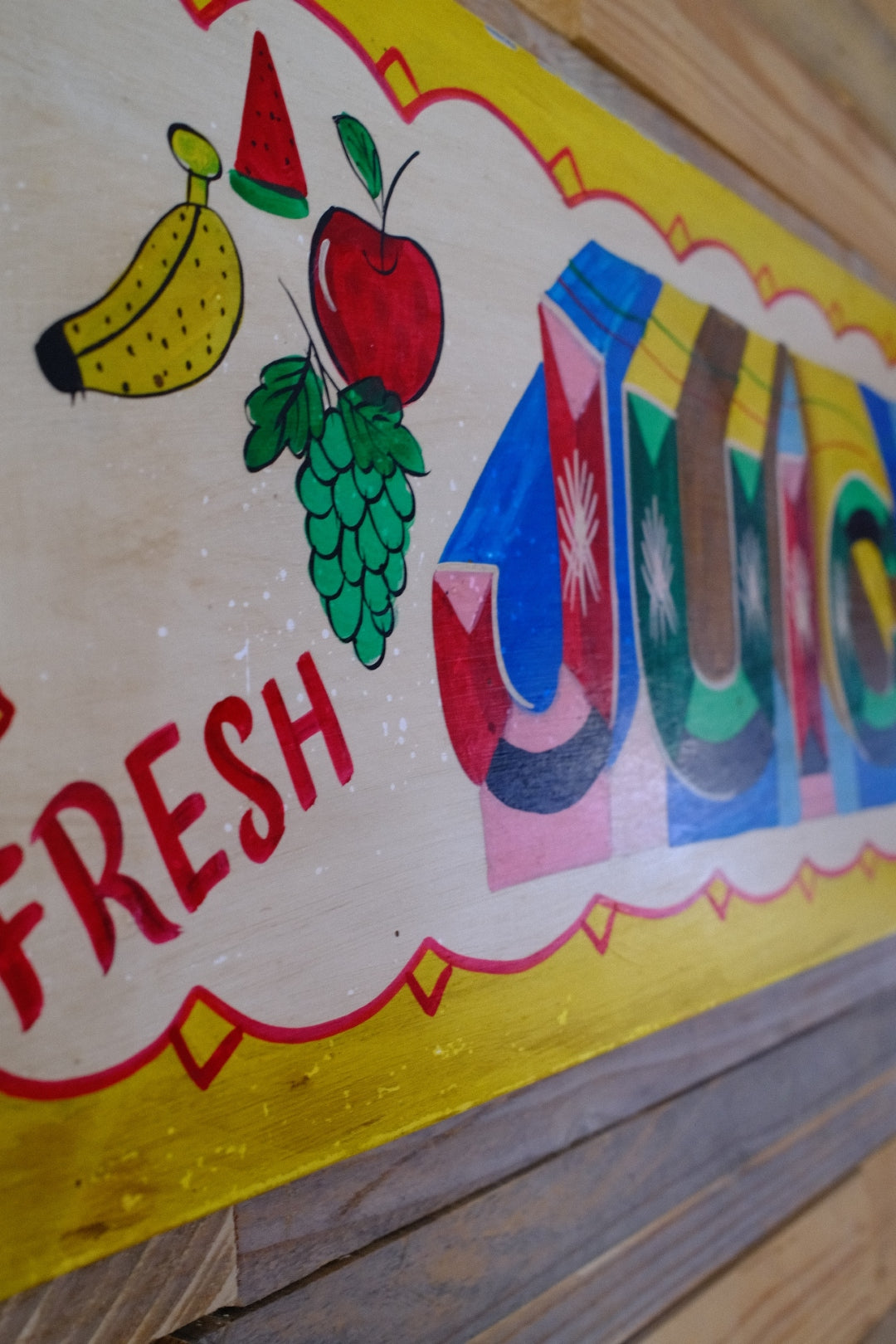Colorful sign with fruit illustrations and the word 'FRESH' on a wooden surface.
