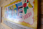 Colorful sign with fruits and the word 'FRESH' on a wooden background
