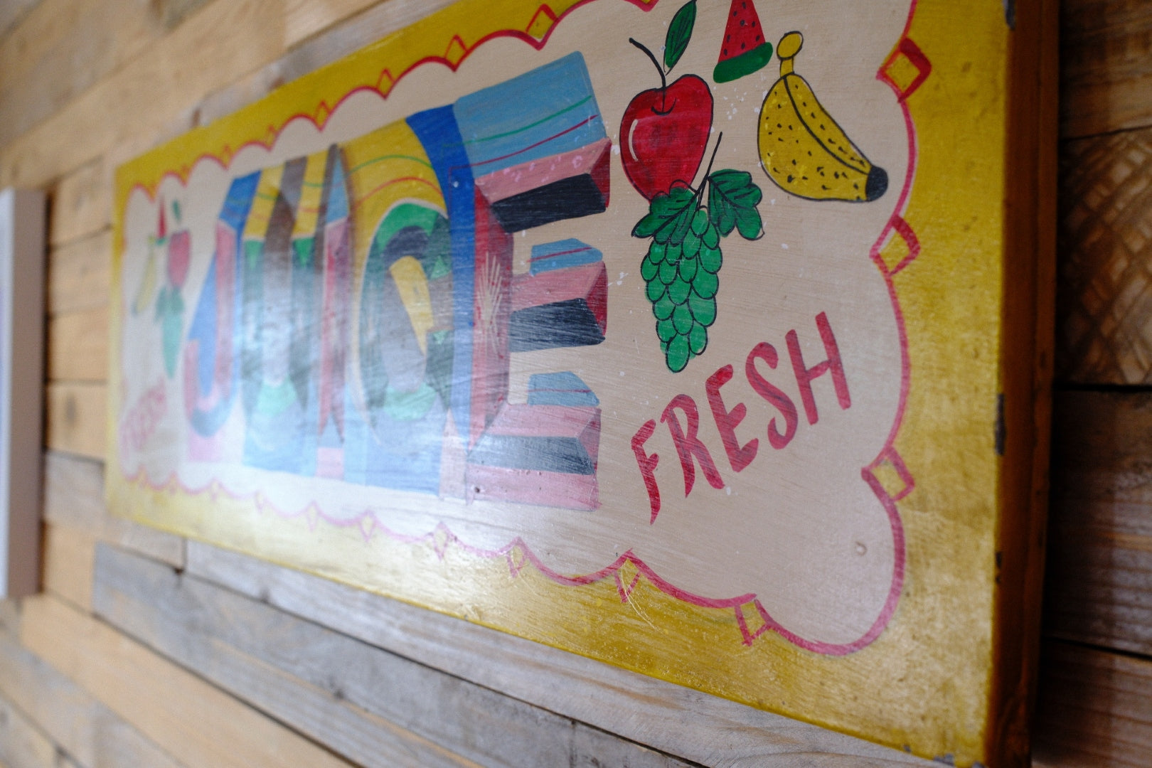 Colorful sign with fruits and the word 'FRESH' on a wooden background