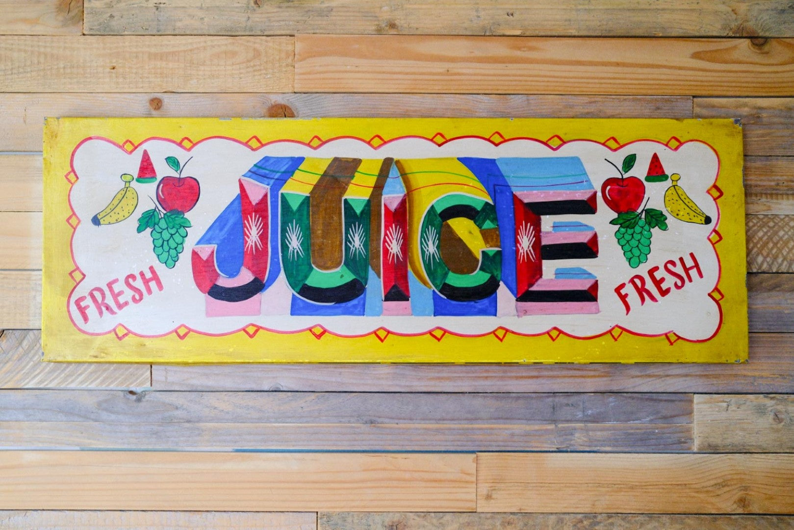 Colourful sign with 'Juice' and fruit illustrations on a wooden background