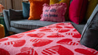 Colorful pillows on a couch with a red patterned blanket in the foreground.