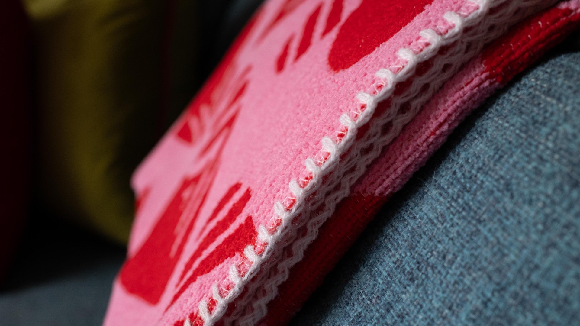 Close-up of a red fabric surface with white stitching on a blurred background