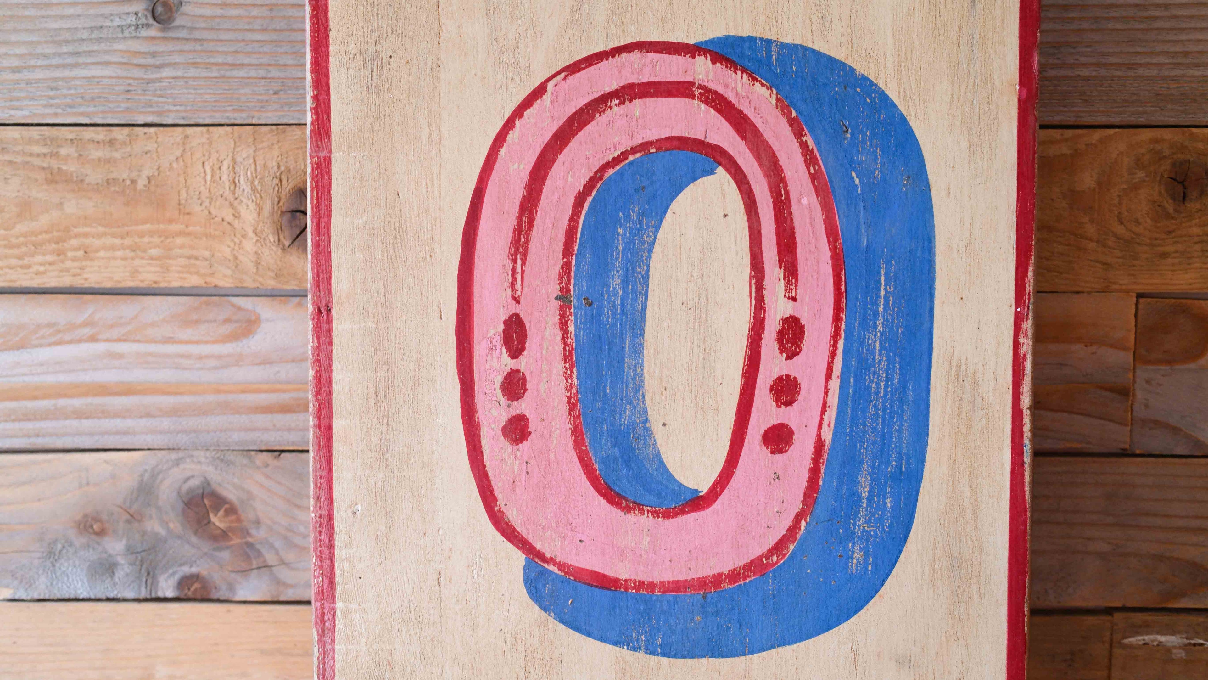 Abstract artwork with pink and blue shapes on a wooden background