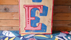 Large wooden letter 'E' with a colorful background