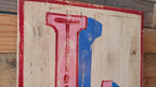 Wooden sign with red and blue letter 'L' on a rustic background