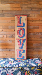 Wooden sign with 'LOVE' in colorful letters against a wooden wall.