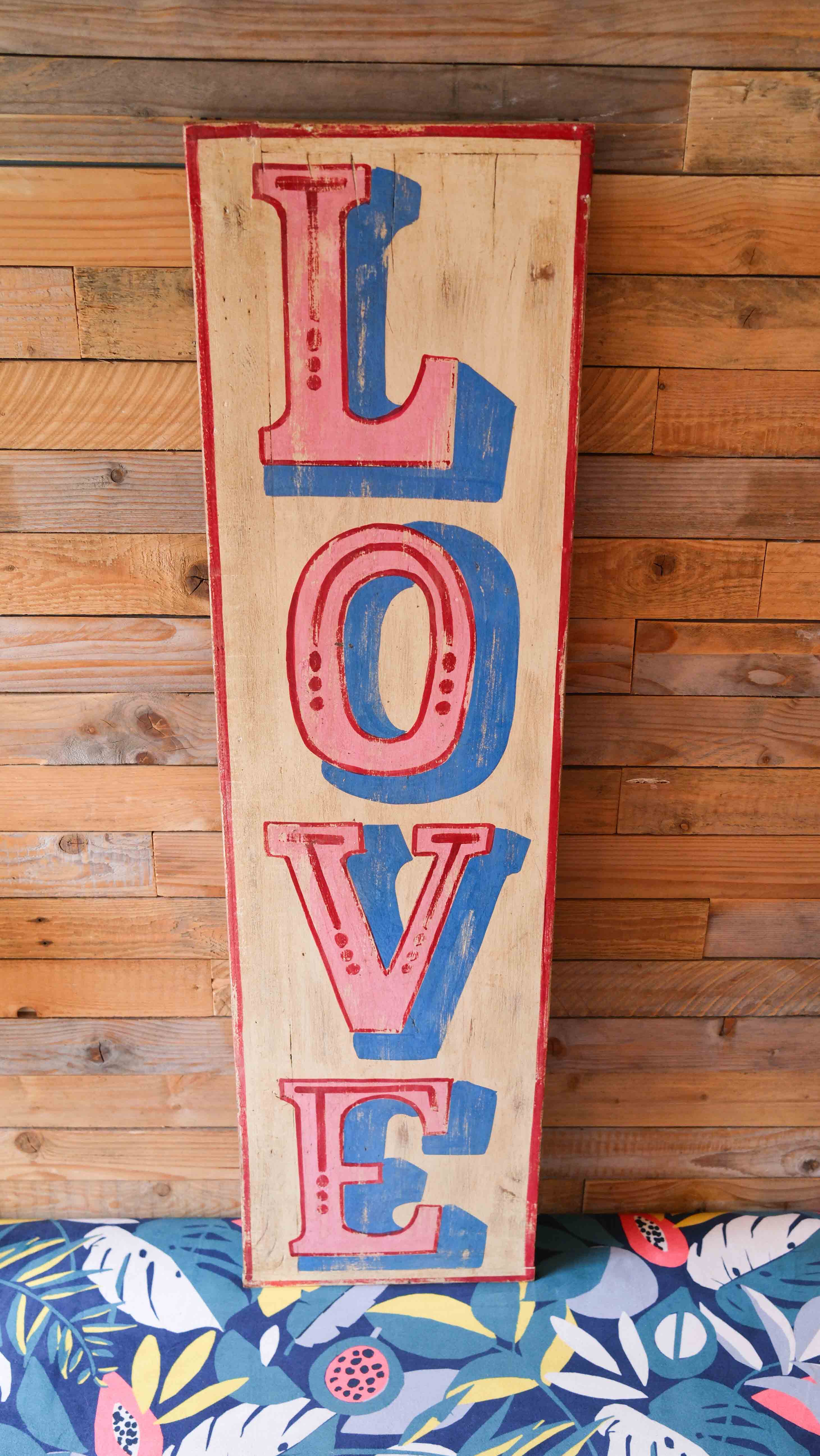 Wooden sign with 'LOVE' in red and blue on a wooden background