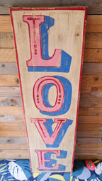 Wooden sign with colorful 'LOVE' letters against a wooden background