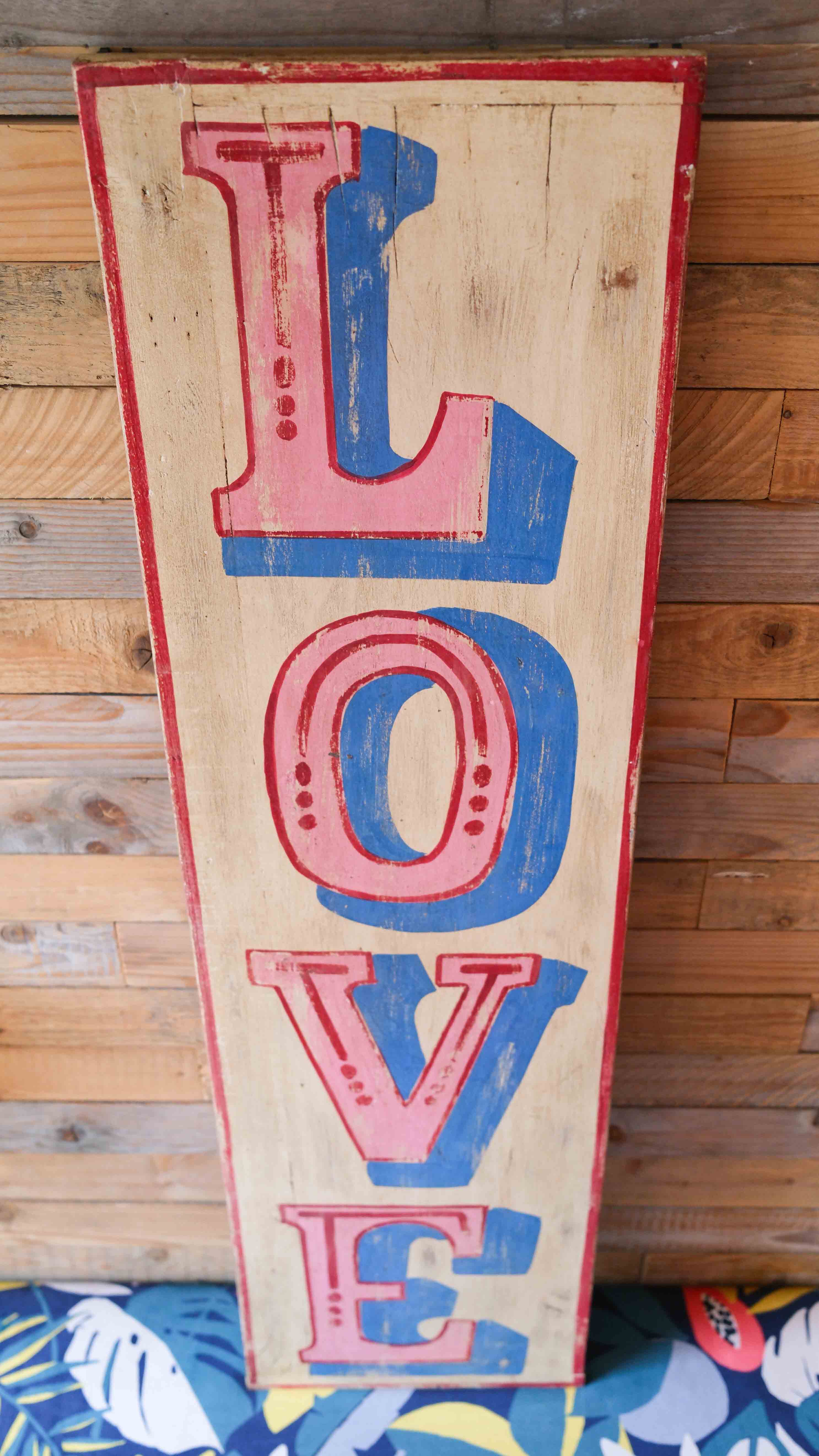 Wooden sign with colorful 'LOVE' letters against a wooden background