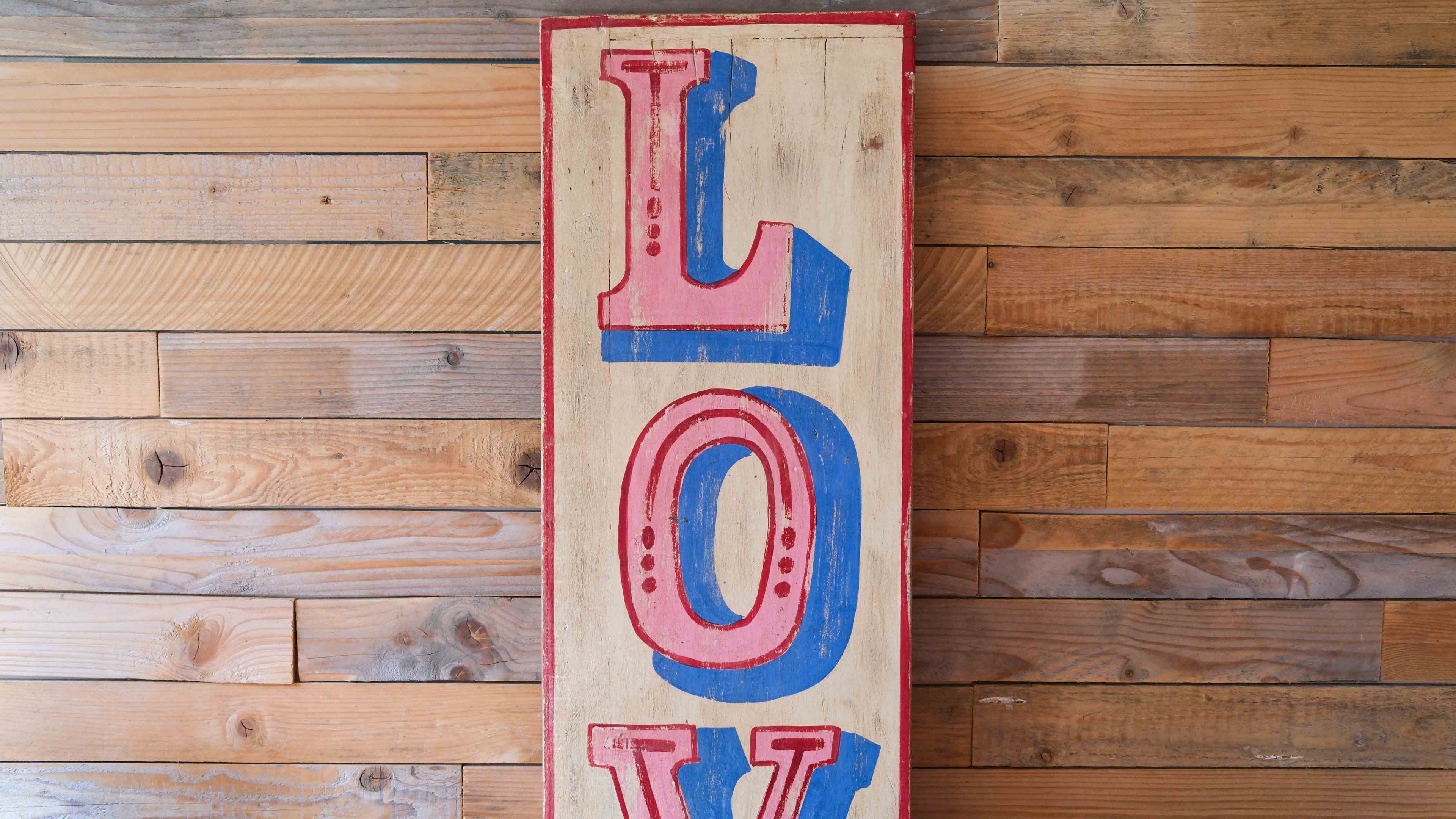 Wooden sign with 'LOVE' in red and blue on a wooden wall.