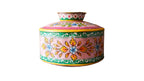 Colorful metal container with floral patterns on a wooden surface