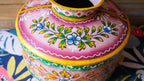 Colorful metal pot with floral patterns on a patterned surface