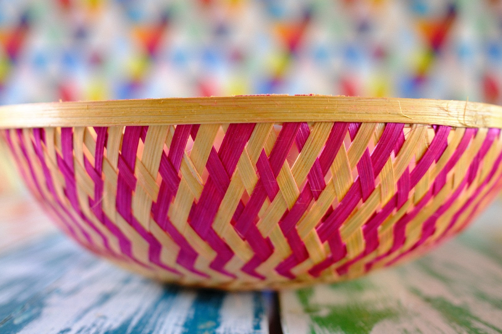 Woven basket with pink and yellow pattern on a colorful background