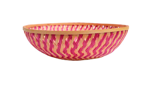 Woven bamboo bowl with pink pattern on a white background