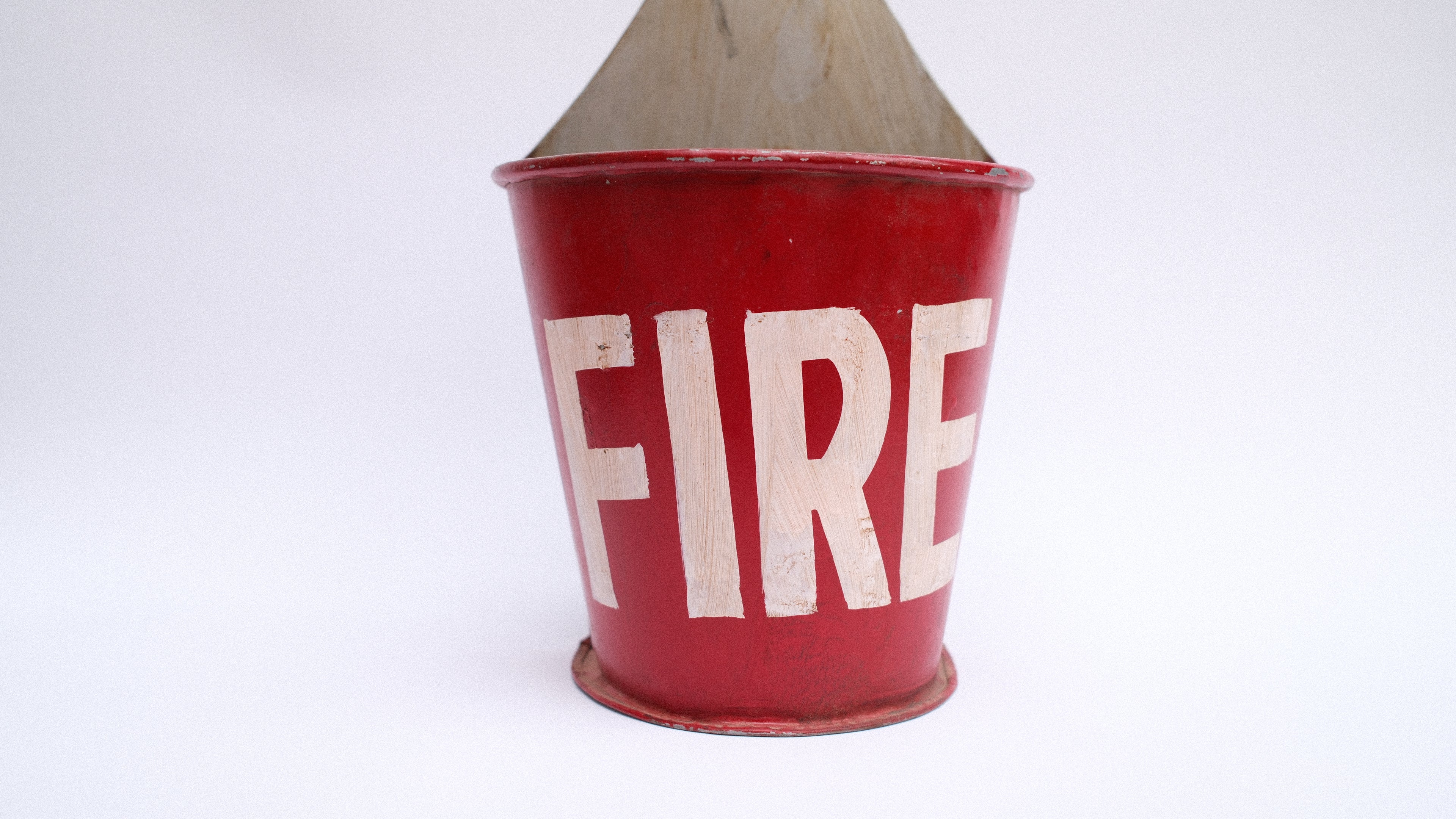 Red fire bucket with 'FIRE' written on it against a white background